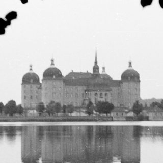 Grand castle reflected in calm lake water.