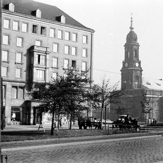 Historic city street with church tower and early 20th-century buildings.