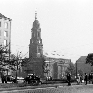 Historic city street with church tower and early 20th-century buildings.