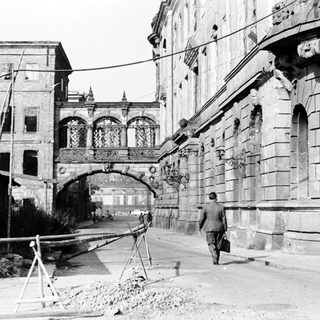 Historic stone bridge and arched buildings under construction.
