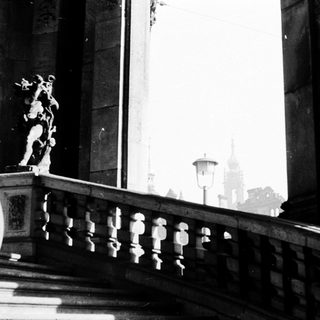 Elegant balcony with classical statues, grand architecture.
