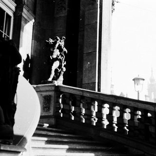 Elegant balcony with classical statues, grand architecture.