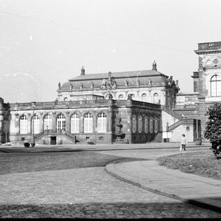 Grand classical palace with arched colonnade and gardens.