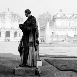 Baroque palace courtyard with statue and grand architecture.