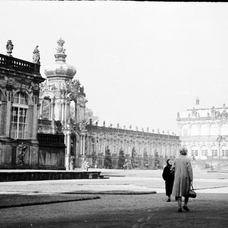 Baroque palace courtyard with two people walking.