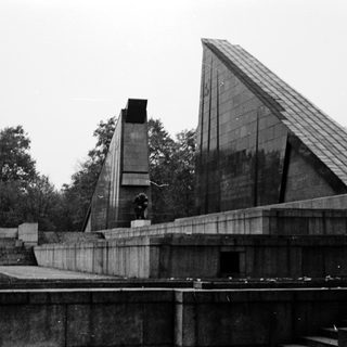 Modernist memorial with geometric architecture and statue.