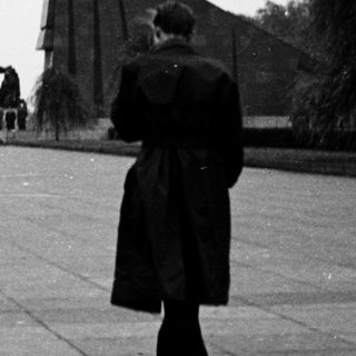 People walking toward memorial with tall triangular structures.