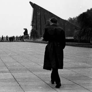 People walking toward memorial with tall triangular structures.