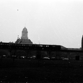 Historic train station with elevated tracks and industrial buildings.