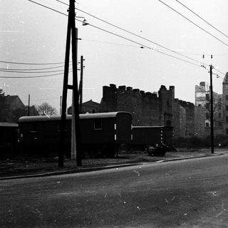 Urban street with old train cars, abandoned buildings, early 20th century.