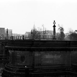 Historic bridge with waterway and cityscape.