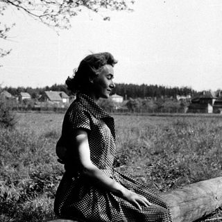 Woman sitting on log in rural field.
