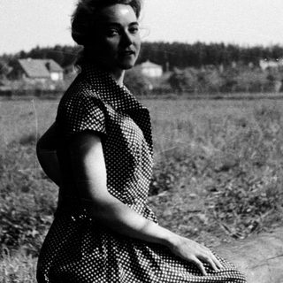 Woman posing outdoors in vintage polka-dot dress.