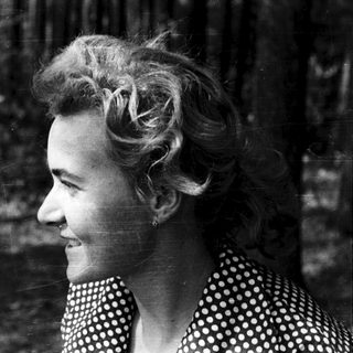 Smiling woman in polka-dot blouse outdoors.