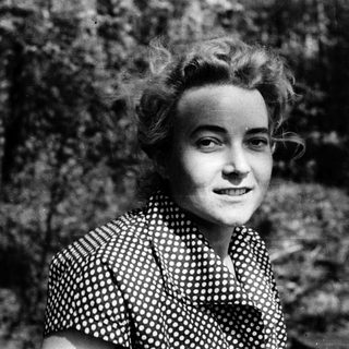 Young woman in patterned blouse outdoors, smiling.
