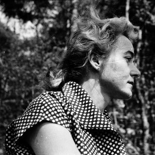 Woman in polka-dot blouse outdoors, mid-20th century.