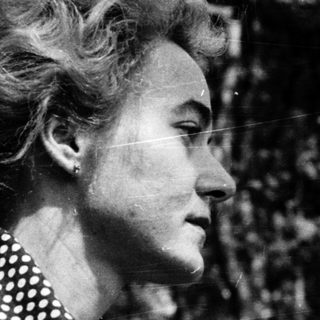 Woman in polka-dot blouse outdoors, mid-20th century.
