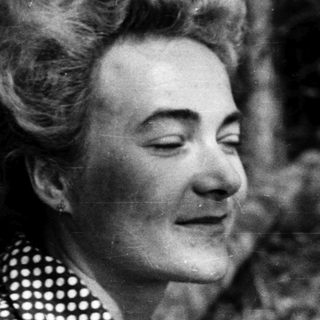 Black-and-white portrait of woman outdoors with curly hair.