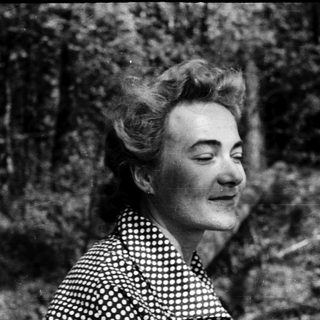 Black-and-white portrait of woman outdoors with curly hair.