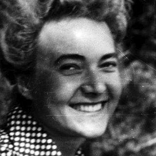 Smiling woman in vintage polka-dot blouse outdoors.