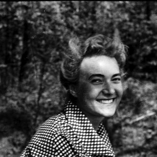 Smiling woman in vintage polka-dot blouse outdoors.