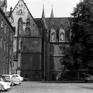Historic European building with classic architecture, vintage cars parked.