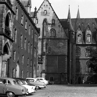 Historic European building with classic architecture, vintage cars parked.