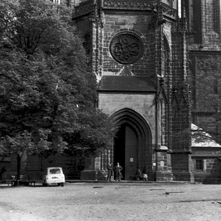 Gothic church facade with arched entrance, vintage cars.
