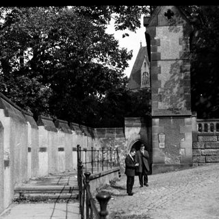 Historic cemetery entrance with stone wall and gravestones.