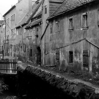 Narrow historic street with aged buildings and canal.