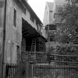 Abandoned buildings with steep, narrow staircase and wooden railings.