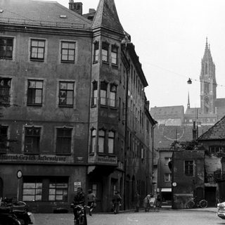 Mid-20th century European street scene with historic buildings.