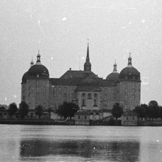 Baroque palace reflected in calm lake water.