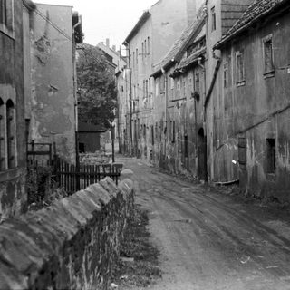 Narrow urban street with aged buildings post-war.