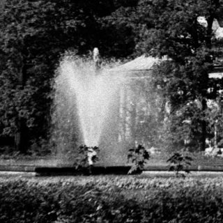 Elegant mansion with fountain in landscaped park.