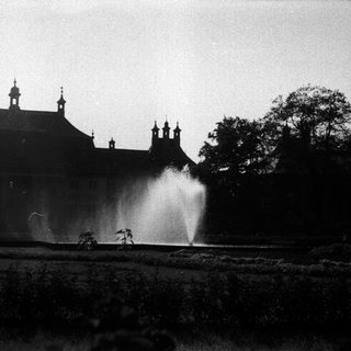 Historic building with fountain in overgrown garden.