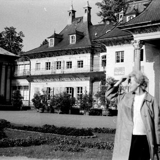 Grand historic building with woman in garden.