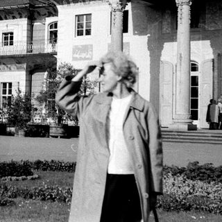 Grand historic building with woman in garden.