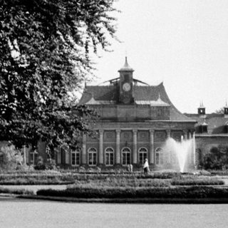 Elegant mansion with fountain in landscaped park.