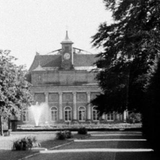 Historic park with lined pathways and grand building.