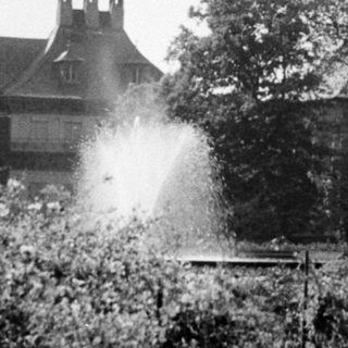 Historic mansion with formal gardens and fountain.