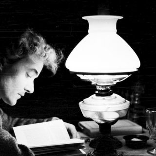 A person reading by candlelight in dim lighting.