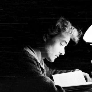 A person reading by candlelight in dim lighting.