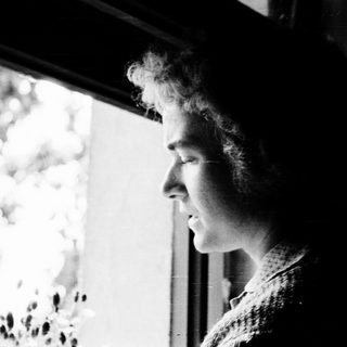 Person gazing thoughtfully outside through a window.