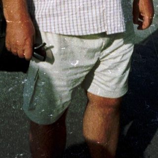 Man walking outdoors in casual attire near palm trees.