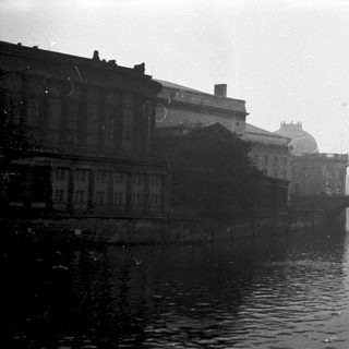 Black-and-white cityscape with canal, bridge, and historic buildings.