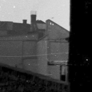 Black-and-white view of church steeple through window.