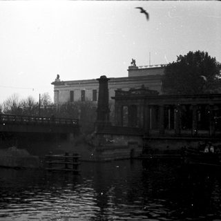 Historic bridge and classical buildings by water.