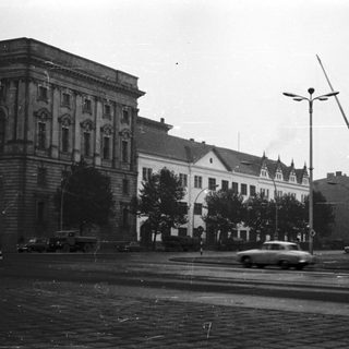 Historic urban street scene with classical buildings and vintage cars.
