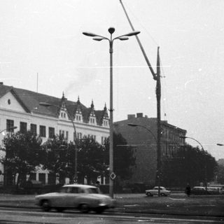 Historic urban street scene with classical buildings and vintage cars.